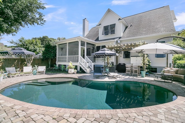 back of house with a sunroom, a patio area, a chimney, and fence