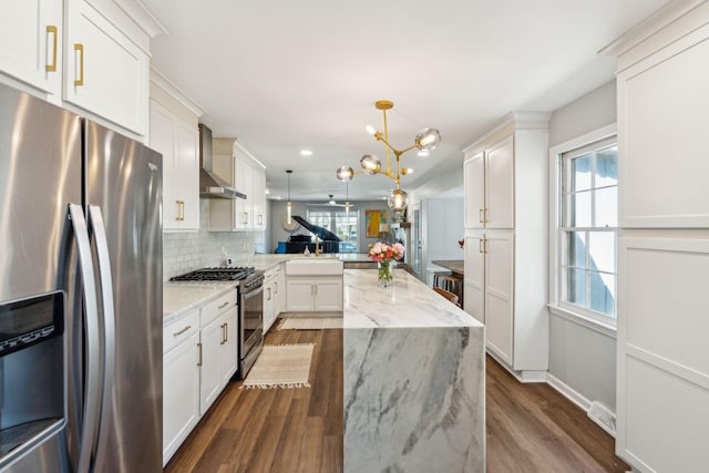 kitchen with stainless steel appliances, kitchen peninsula, dark hardwood / wood-style floors, wall chimney range hood, and pendant lighting