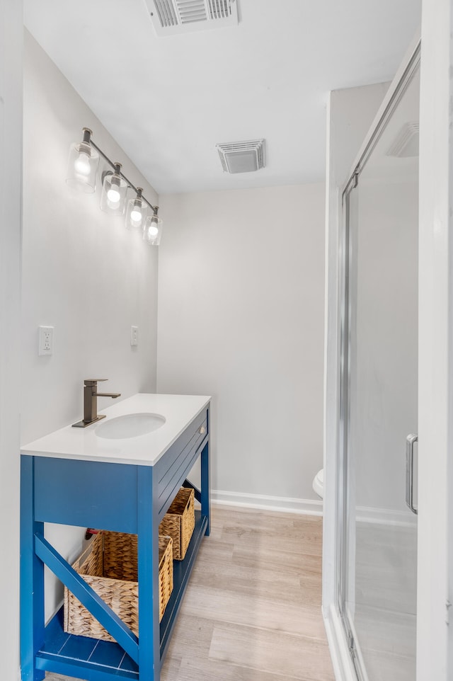 bathroom with vanity, toilet, hardwood / wood-style flooring, and walk in shower