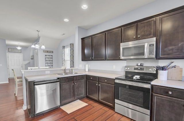 kitchen featuring sink, stainless steel appliances, dark hardwood / wood-style floors, kitchen peninsula, and decorative light fixtures