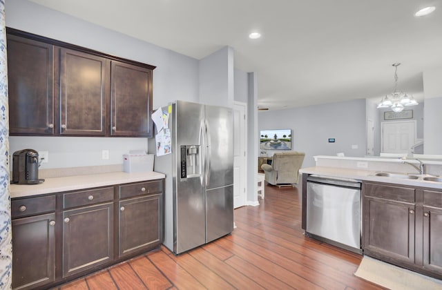 kitchen with sink, appliances with stainless steel finishes, decorative light fixtures, dark brown cabinets, and a chandelier