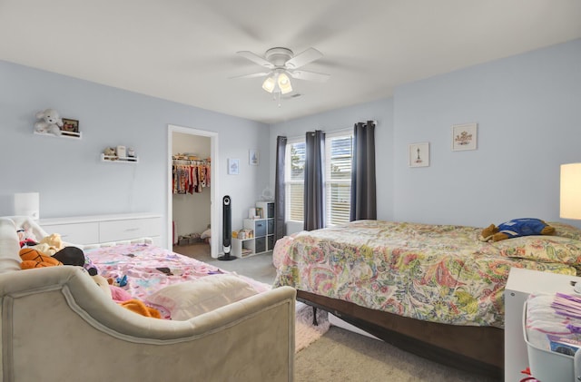 carpeted bedroom with a walk in closet, a closet, and ceiling fan