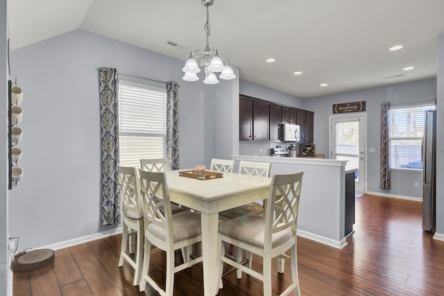 dining room featuring vaulted ceiling, dark hardwood / wood-style flooring, and a chandelier