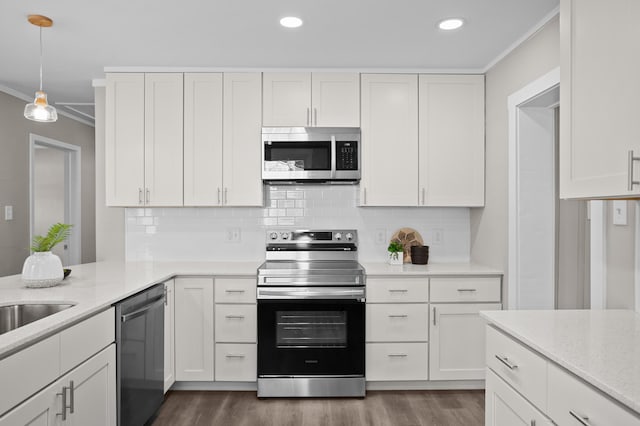 kitchen featuring white cabinetry, ornamental molding, stainless steel appliances, and decorative light fixtures