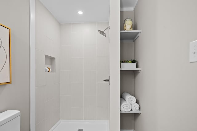 bathroom featuring a tile shower and toilet