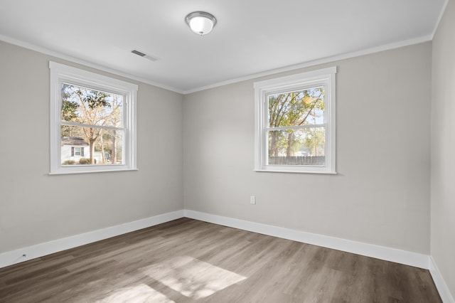 spare room with ornamental molding, a wealth of natural light, and light hardwood / wood-style floors