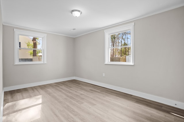 spare room with crown molding and light wood-type flooring