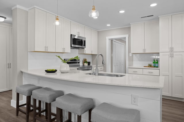 kitchen featuring sink, hanging light fixtures, appliances with stainless steel finishes, light stone countertops, and white cabinets