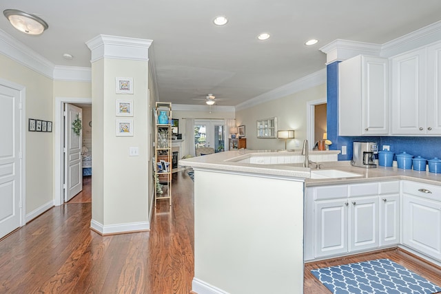 kitchen featuring ornamental molding, open floor plan, white cabinetry, and wood finished floors