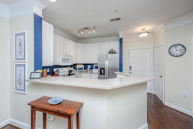 kitchen with white microwave, a peninsula, visible vents, stainless steel refrigerator with ice dispenser, and range