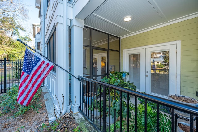 view of exterior entry featuring french doors and fence