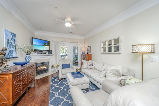 living area with crown molding, dark wood finished floors, visible vents, a fireplace with flush hearth, and ceiling fan