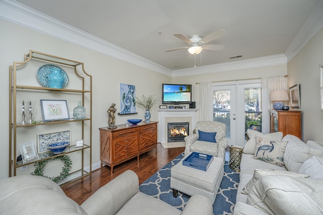 living area with visible vents, a fireplace with flush hearth, ornamental molding, wood finished floors, and french doors