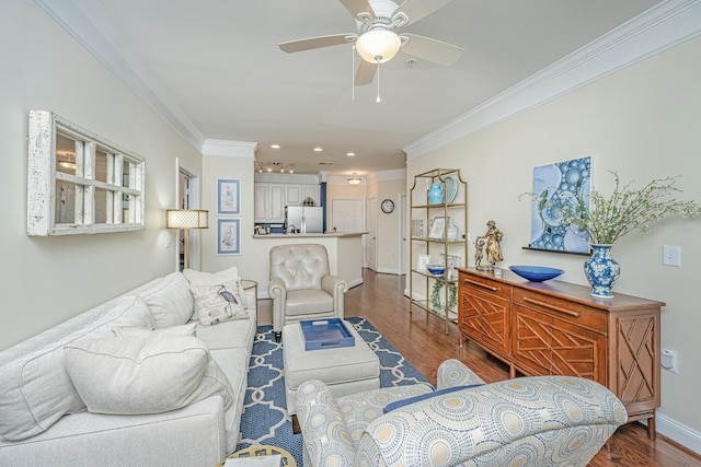 living area with ornamental molding, dark wood finished floors, a ceiling fan, and baseboards