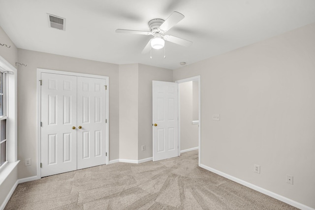 unfurnished bedroom with ceiling fan, a closet, and light carpet