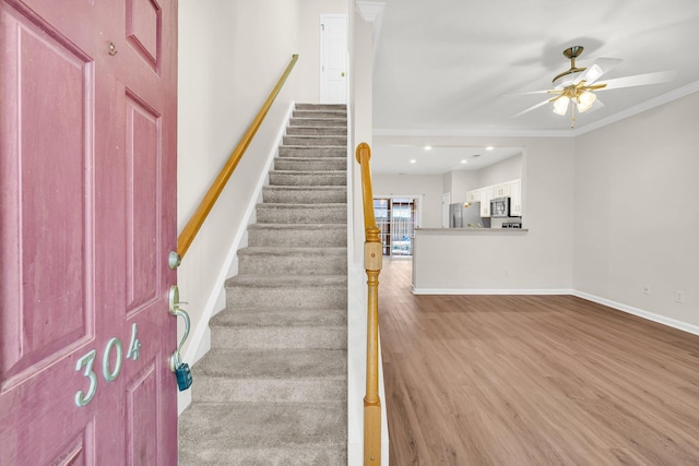 stairway featuring ceiling fan, crown molding, and hardwood / wood-style flooring