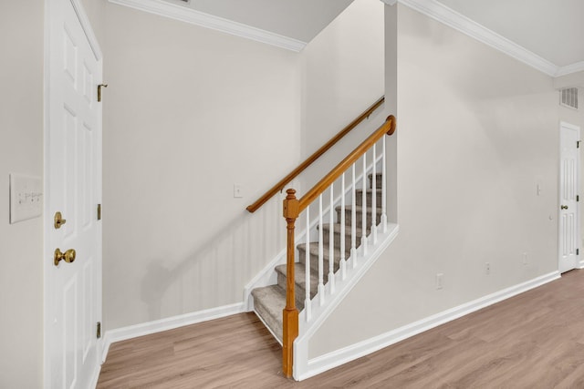 stairway with wood-type flooring and crown molding