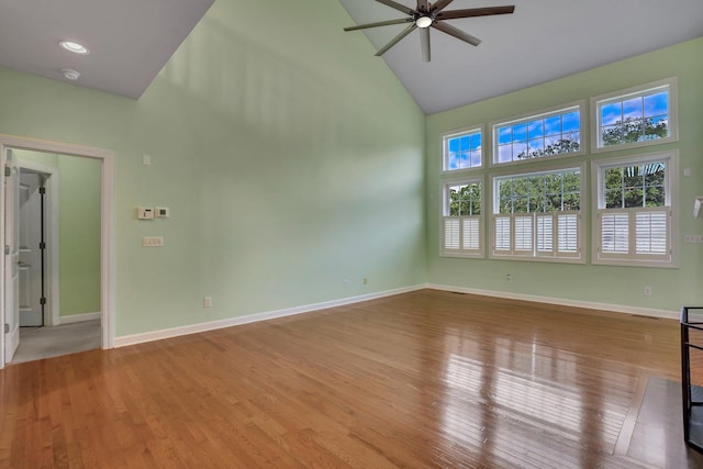 spare room with light wood-style flooring, baseboards, high vaulted ceiling, and a ceiling fan