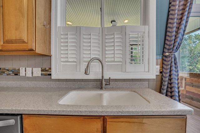 kitchen featuring a sink, tasteful backsplash, and light stone countertops