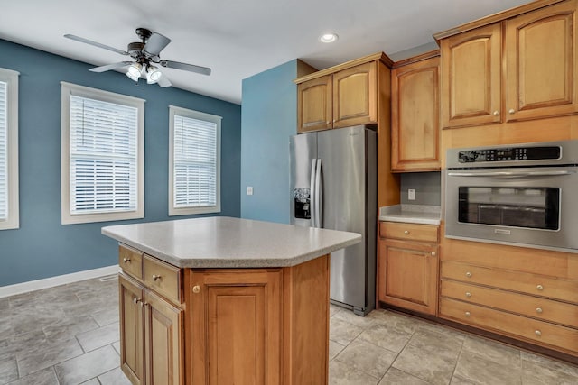 kitchen with appliances with stainless steel finishes, brown cabinetry, a kitchen island, and light countertops