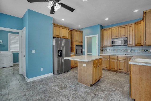 kitchen with washer / clothes dryer, a center island, a sink, light countertops, and stainless steel appliances