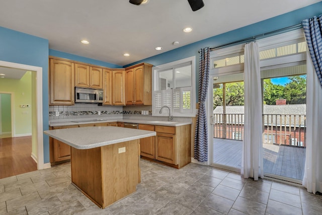 kitchen featuring a sink, a kitchen island, stainless steel microwave, light countertops, and black electric stovetop