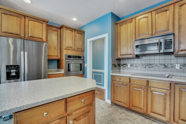 kitchen with stainless steel appliances, brown cabinetry, and tasteful backsplash