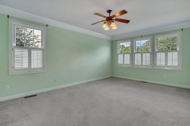 carpeted spare room with a wealth of natural light, baseboards, and ornamental molding