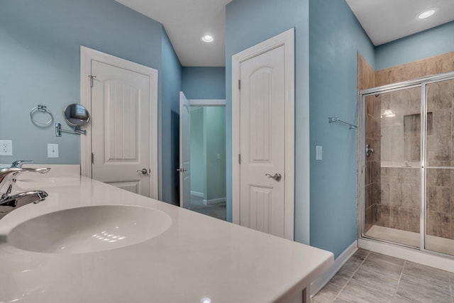 bathroom featuring a sink, a closet, double vanity, and a stall shower