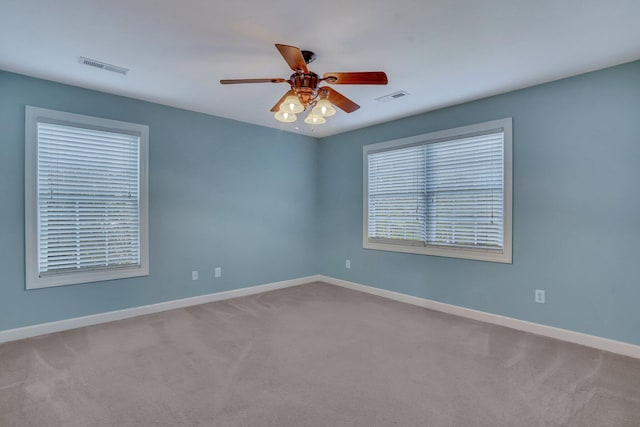 carpeted spare room featuring a ceiling fan, visible vents, and baseboards