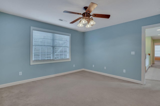 empty room with baseboards, ceiling fan, visible vents, and light carpet