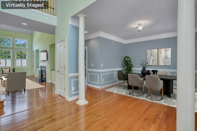 home office with a glass covered fireplace, wood finished floors, and ornate columns