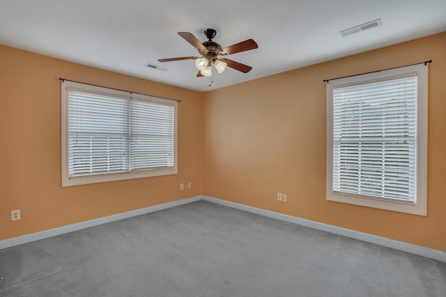 empty room featuring ceiling fan, visible vents, and baseboards