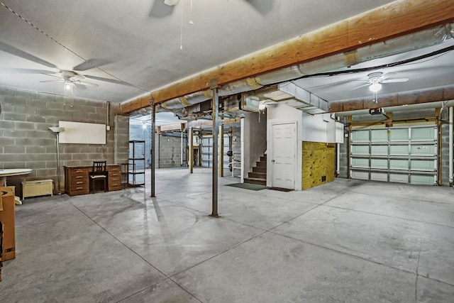 basement featuring ceiling fan and concrete block wall