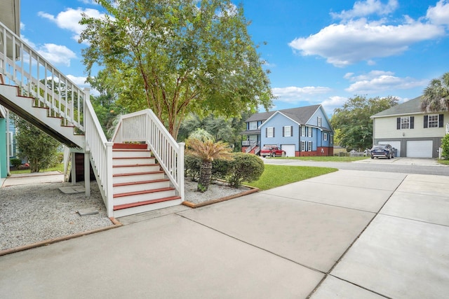 view of front of property featuring a residential view, stairs, a garage, and driveway