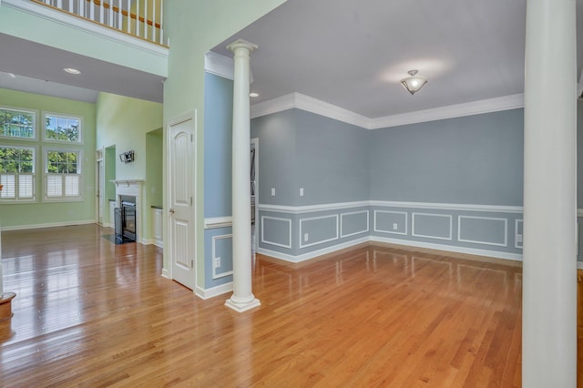 spare room with a fireplace with flush hearth, wood finished floors, and ornate columns