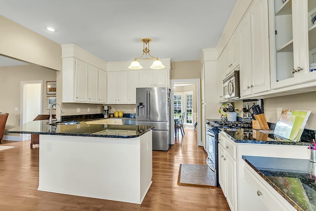 kitchen featuring stainless steel appliances, a peninsula, a sink, white cabinets, and pendant lighting