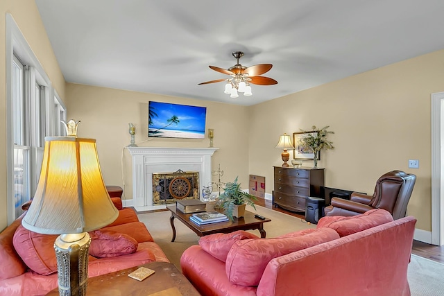 living room featuring ceiling fan, a fireplace with flush hearth, and baseboards