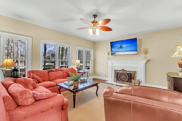 living area featuring a fireplace, baseboards, and a ceiling fan