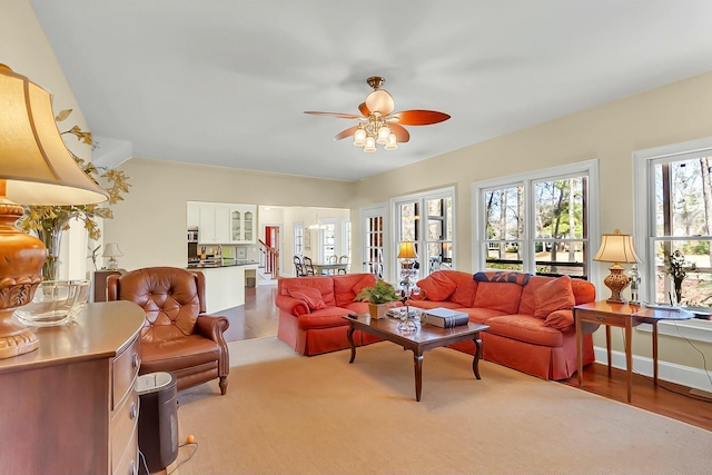 living room with a ceiling fan, french doors, baseboards, and wood finished floors