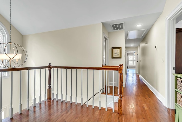 corridor with attic access, wood-type flooring, visible vents, and an upstairs landing