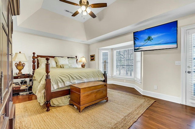 bedroom with a ceiling fan, visible vents, baseboards, and wood finished floors