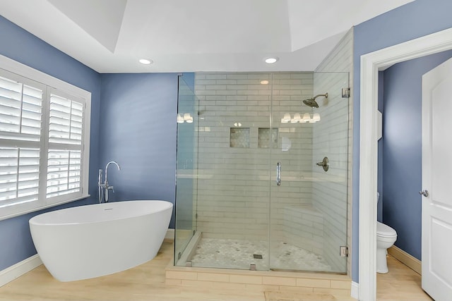 bathroom with a freestanding bath, a shower stall, toilet, and baseboards