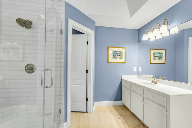 full bath with vanity, a shower stall, baseboards, and wood finished floors