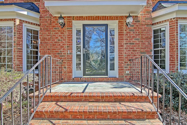 doorway to property featuring a porch and brick siding