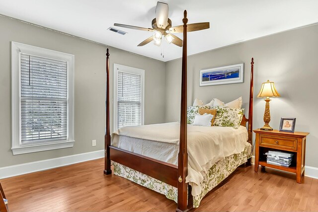 bedroom featuring multiple windows, wood finished floors, visible vents, and baseboards