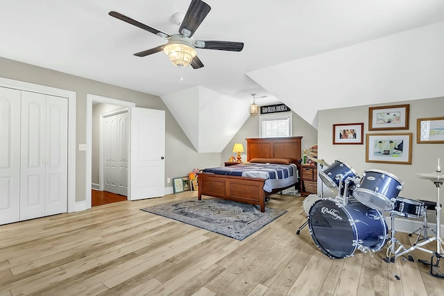 bedroom with lofted ceiling, ceiling fan, light wood-style flooring, multiple closets, and baseboards