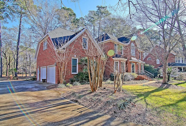 view of front of house with driveway, brick siding, and an attached garage