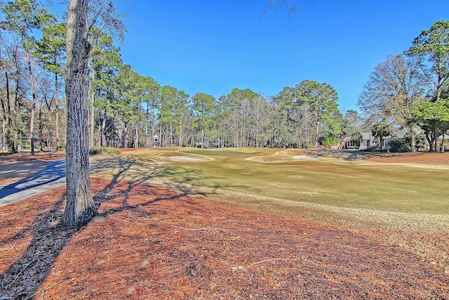 view of home's community with view of golf course and a lawn