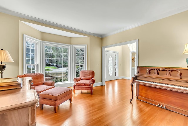 living area featuring ornamental molding, light wood-type flooring, and baseboards